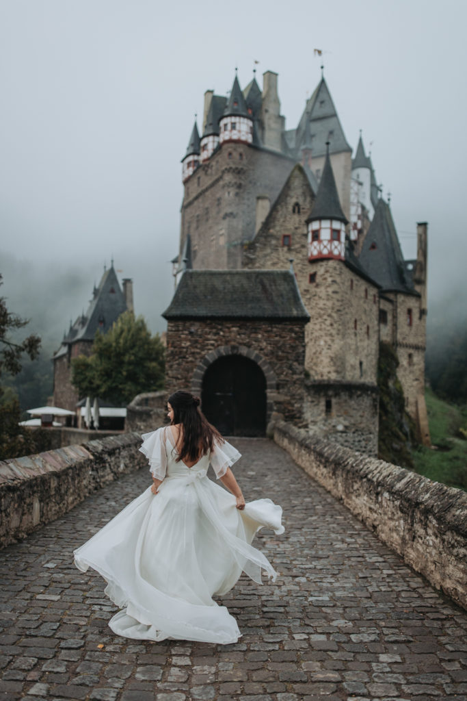 A woman in a wedding dress spins during her Burg Eltz elopement