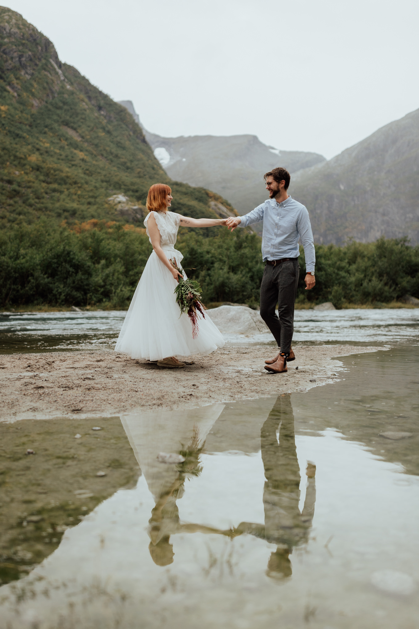 A couple eloping in Norway dance under cloudy skies