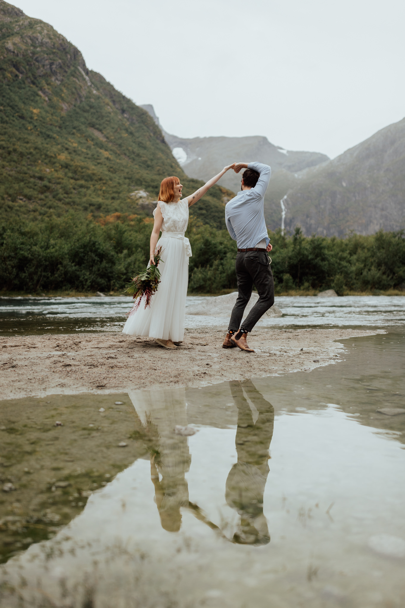 A couple eloping in Norway spin near a lake