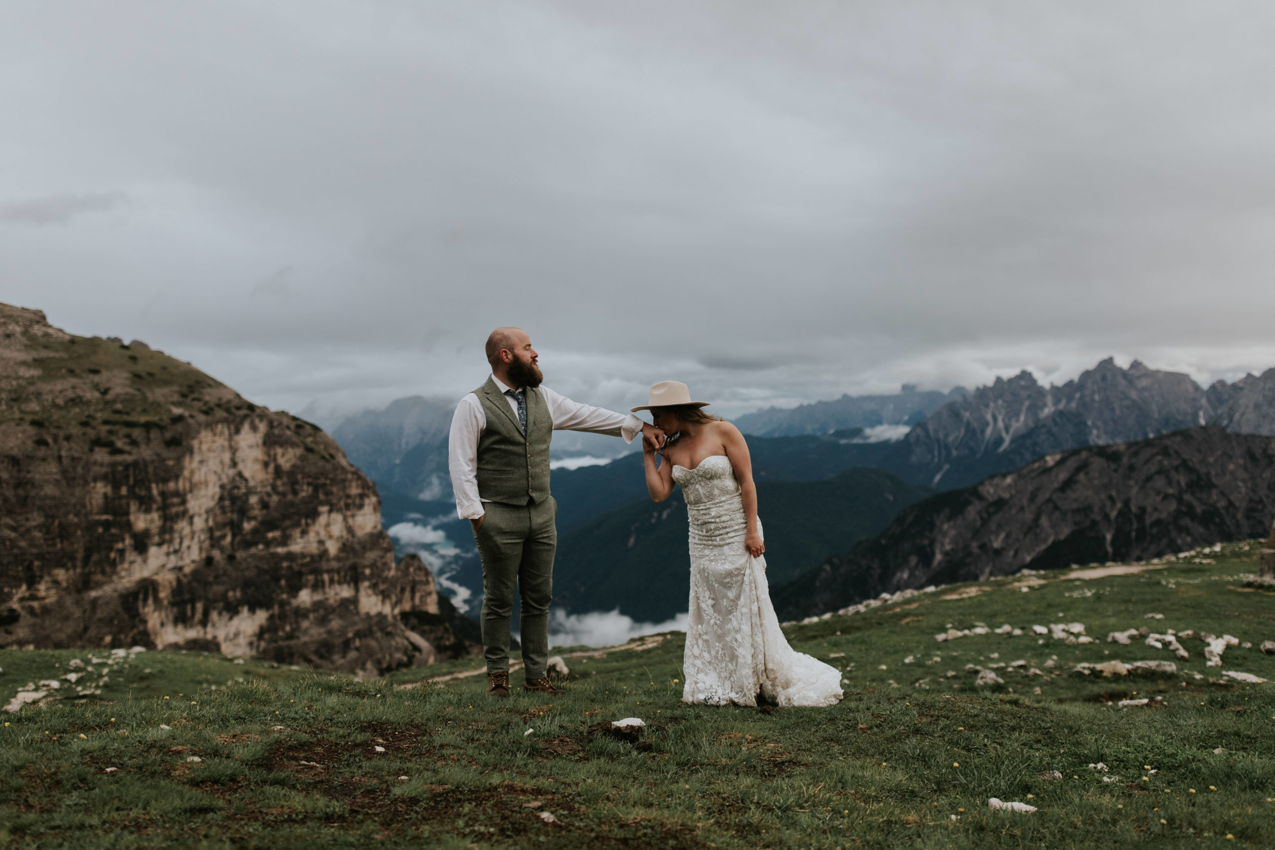A couple stands on the Tre Cime hiking trail on their elopement day, kissing and cuddling