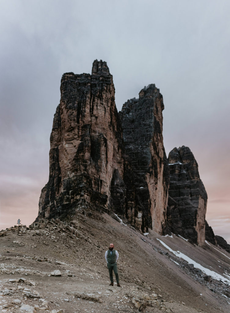 man stands in his wedding suit under the famous tre cime peaks