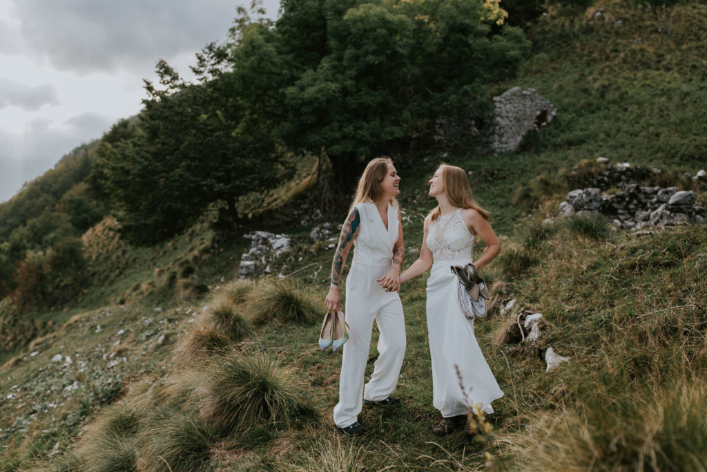 Lesbian couple laughs and holds hands during their Slovenia mountain elopement
