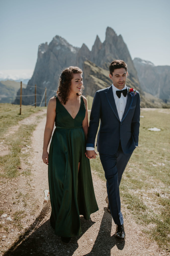 A couple walks away from the Seceda UNESCO peaks during their  Dolomites elopement shoot