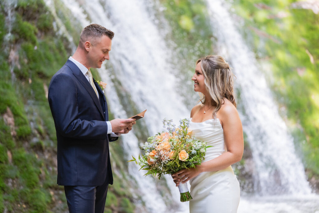 A couple in wedding clothes reads private vows next to a hidden waterfall along the shores of Lake Como on their elopement day.
