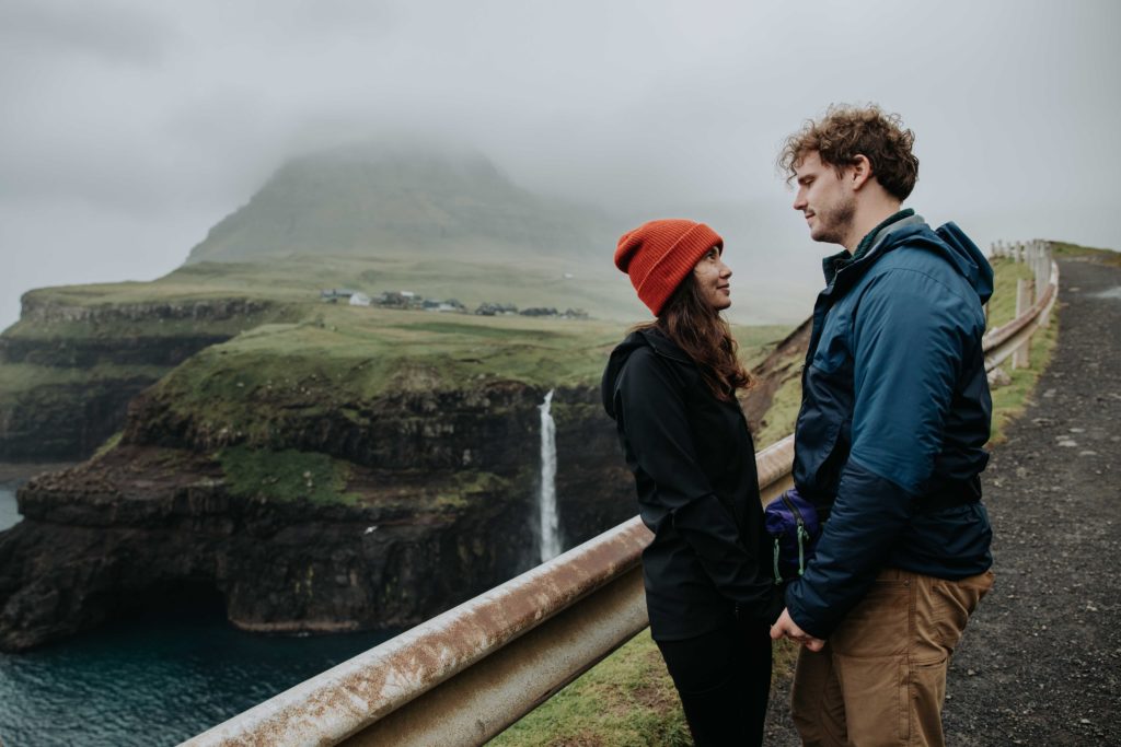 Couple stands near a waterfall in the faroe islands during their elopement.