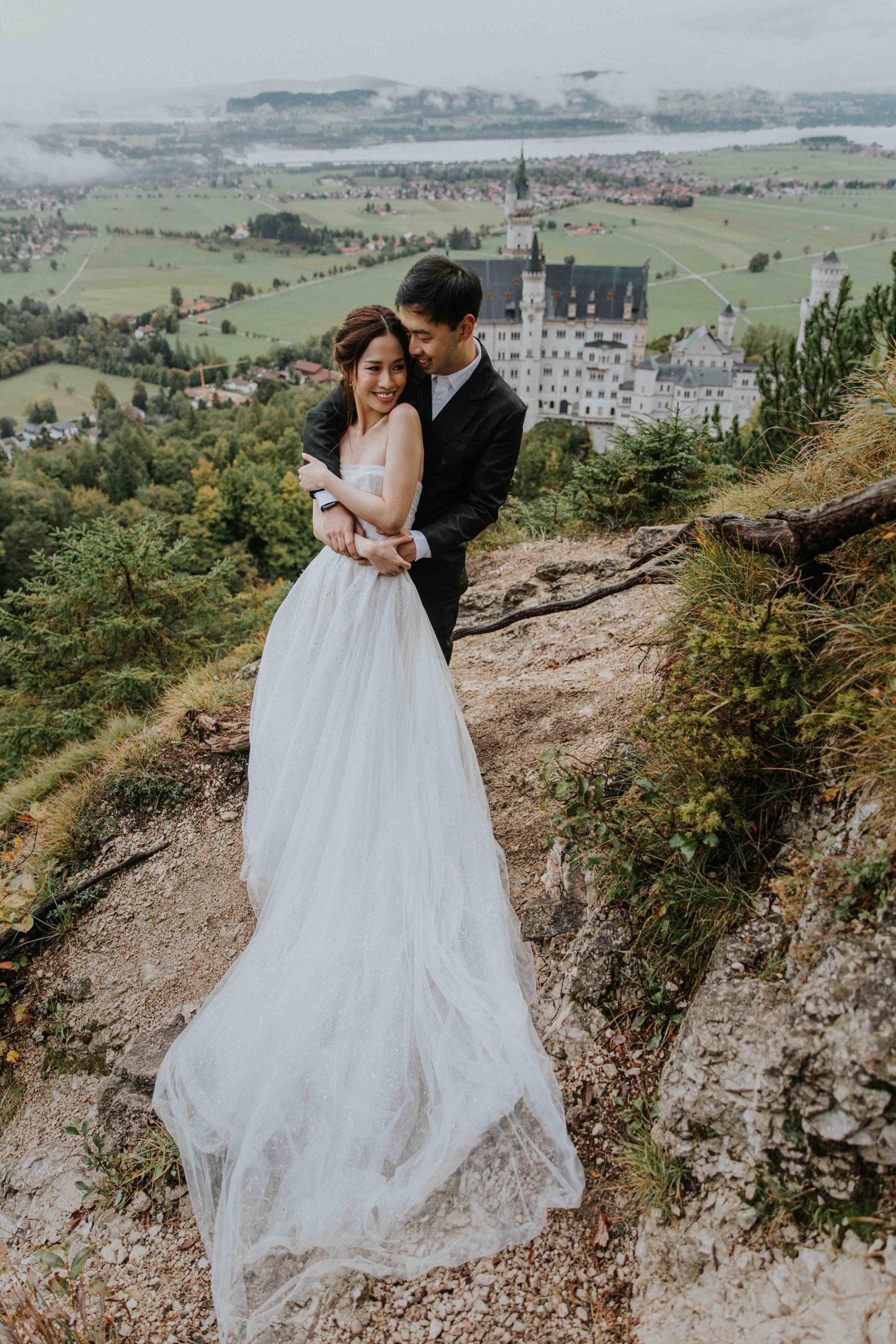 A couple embraces during their Pre wedding photo session outside schloss neuschwanstein in Germany