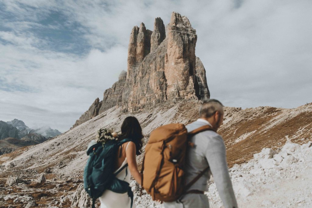 This is an image of a couple walking near the Tre Cime peaks during their Dolomites elopement. They are holding hands, slightly out of focus, facing the peaks.