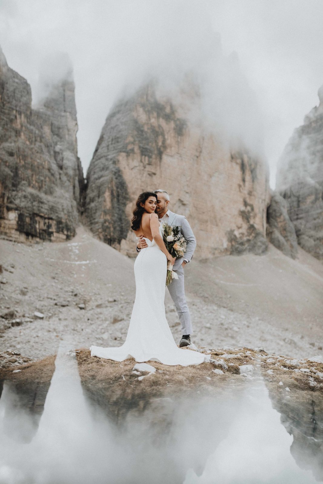 A couple stands in front of one of the Dolomites most famous peaks, Tre Cime, posing for wedding photos on their elopement day