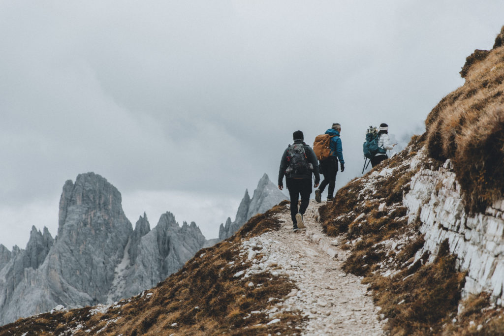 A group of hikers walk down a steep trail in the Dolomites toward Cadini di Misurina