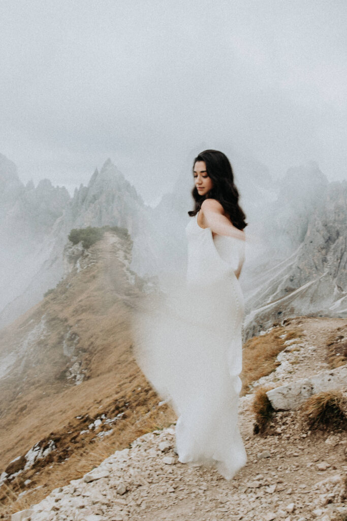 A woman in a wedding dress stands near the Cadini di Misurina viewpoint on her elopement day.