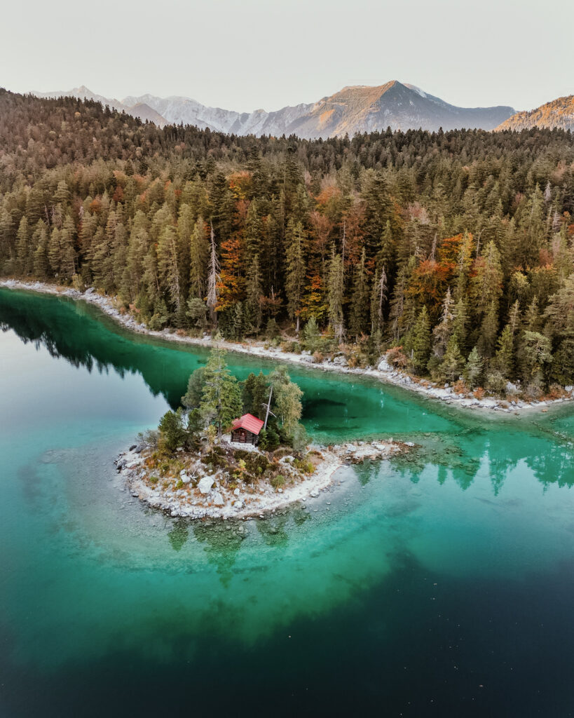 A bird's eye view of Eibsee in Bavaria Germany with a small island and red roofed hut.