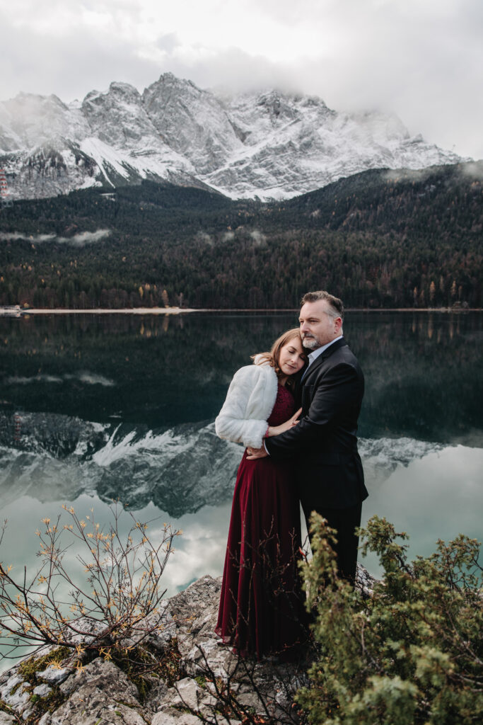 A couple embraces during their elopement on the Bavarian lake of Eibsee on a winter day