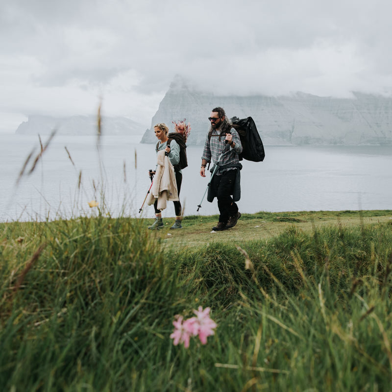 A couple hike across a grassy field in the Faroe Islands on their elopement day