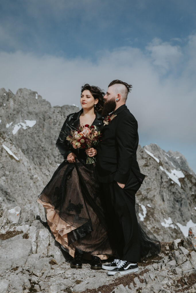A couple dressed in black formal attire pose for Nordkette elopement photos on the top of Innsbruck, in Austria