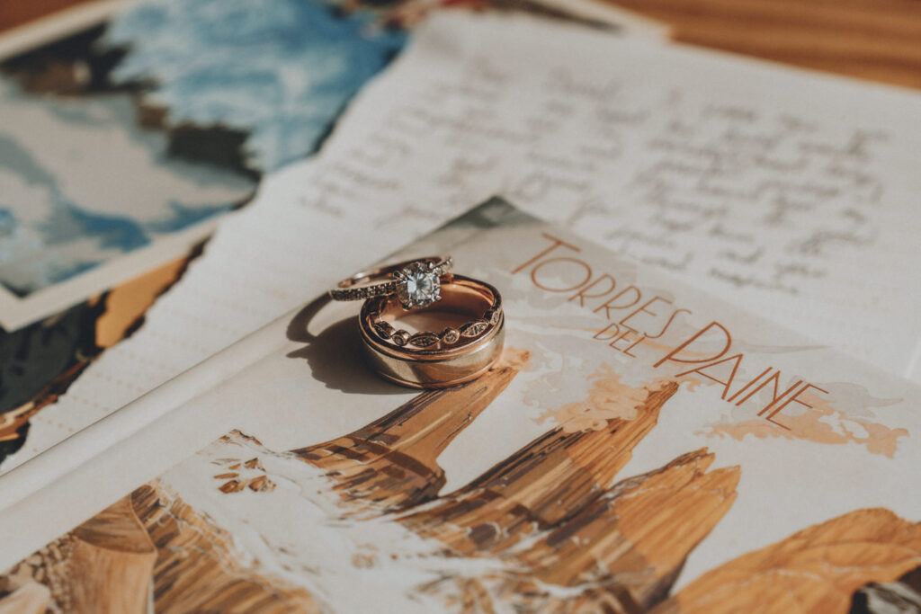 A collection of wedding bands sits on top of an illustration of Torres del Paine and wedding vows during an elopement in Patagonia.