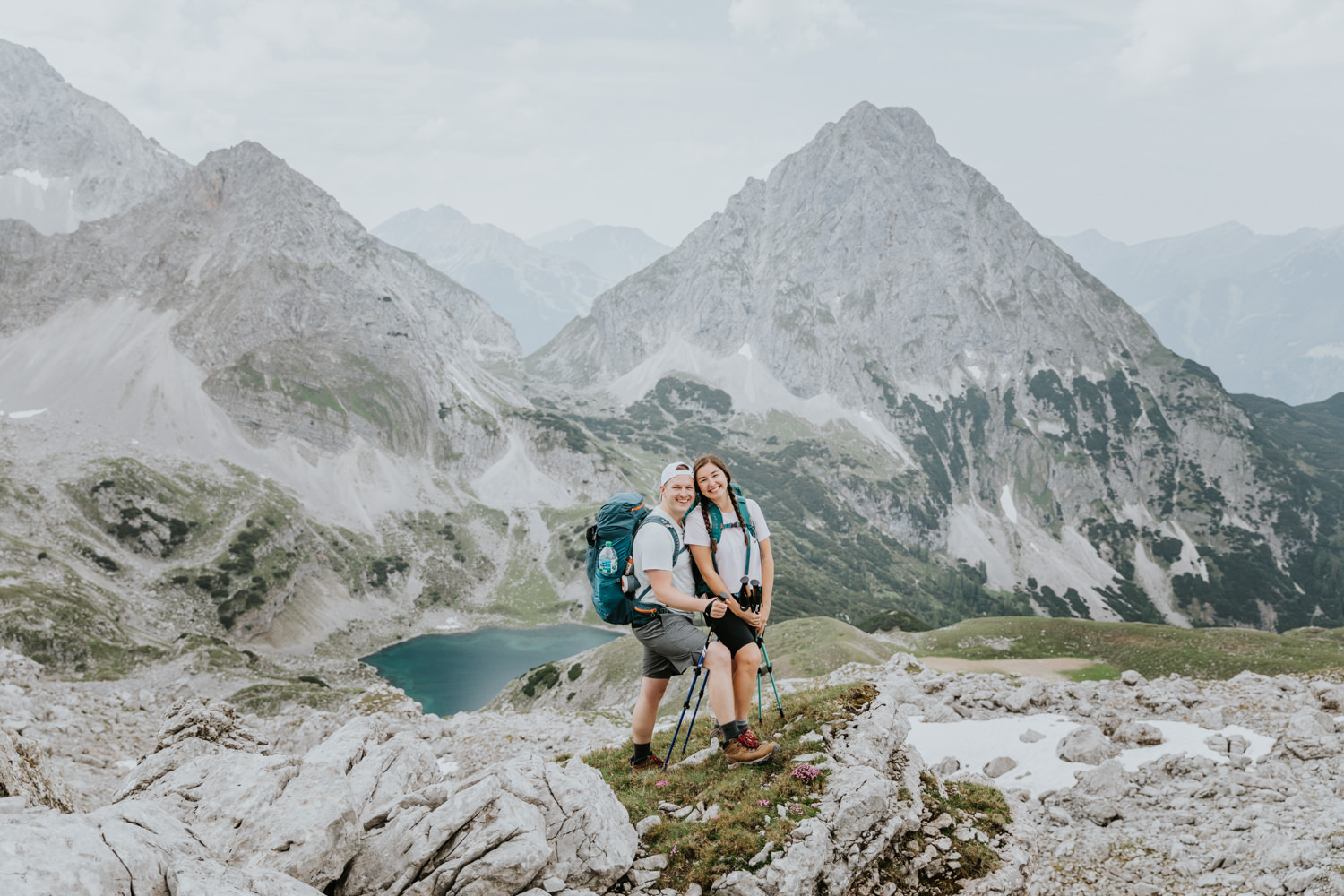 A couple hiking on their elopement day pose smiling under the Austrian Zugspitze, framed by tall rocky mountains