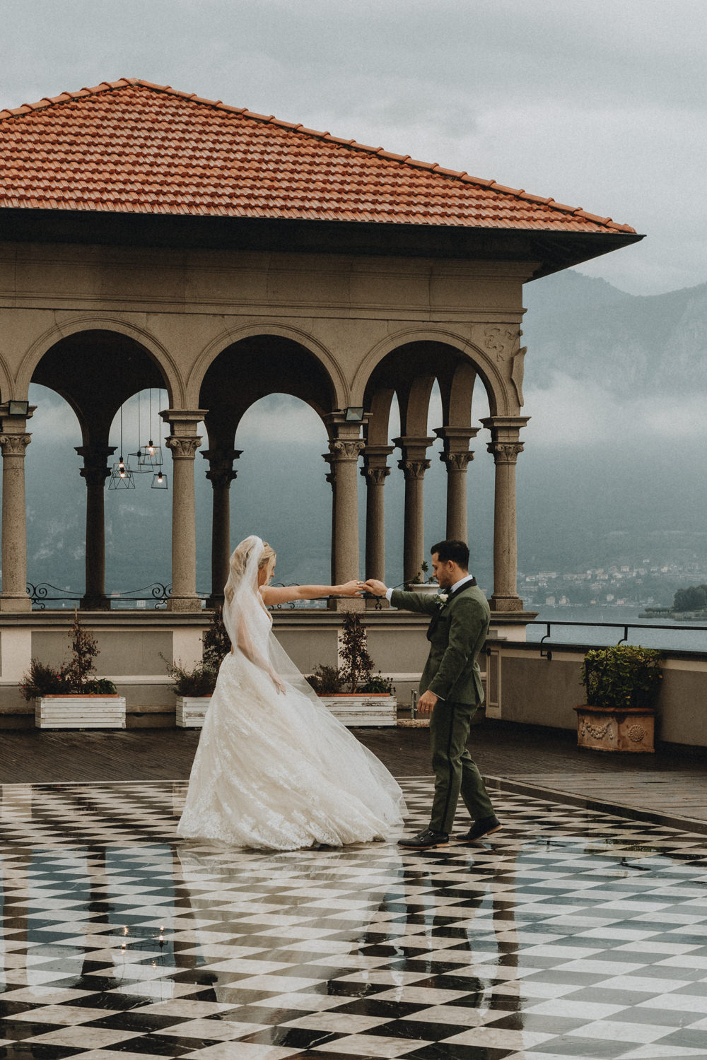 A couple dance on the terrace of a villa in wedding outfits as they celebrate their lake Como elopement.