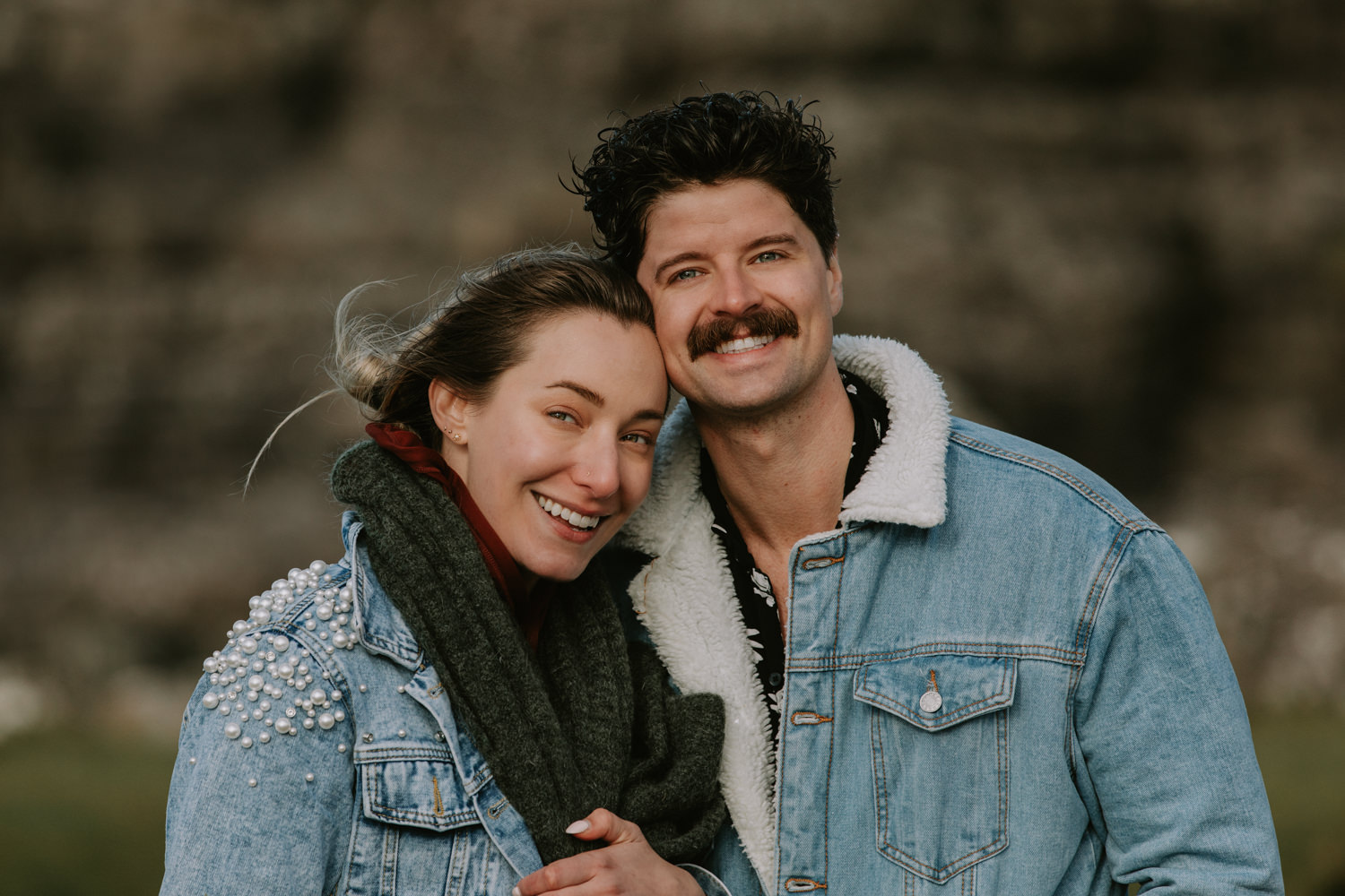 A white hetero couple smile for the camera wearing matching jean jackets for their elopement in the Faroe Islands 