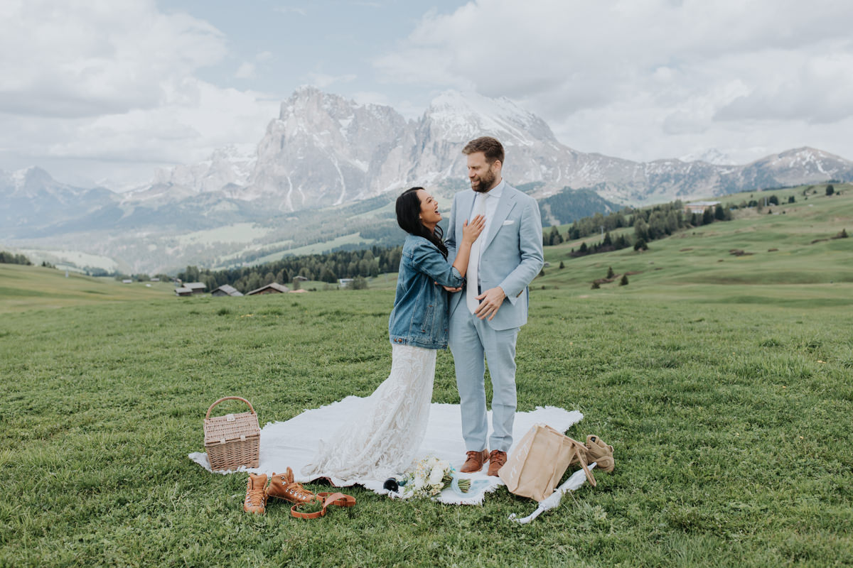 A couple in wedding attire enjoys a picnic in the Dolomites on their elopement day