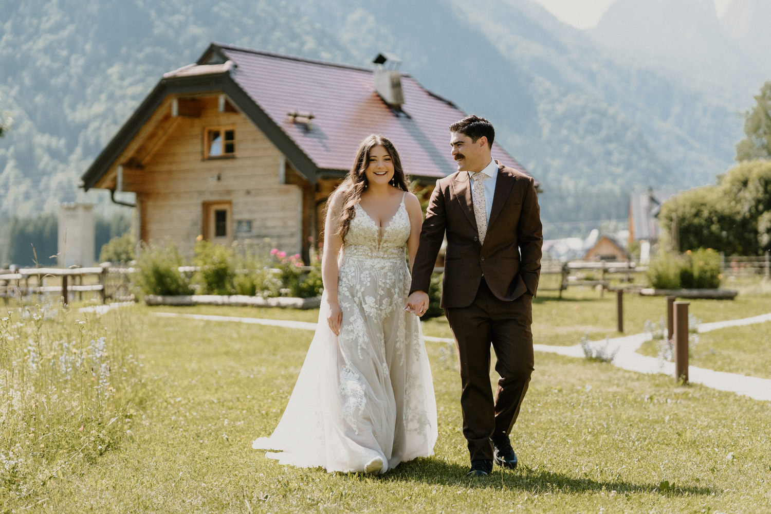 A couple dressed in wedding dress and brown suit hold hands laughing as they have a first look during their mountain elopement in Slovenia