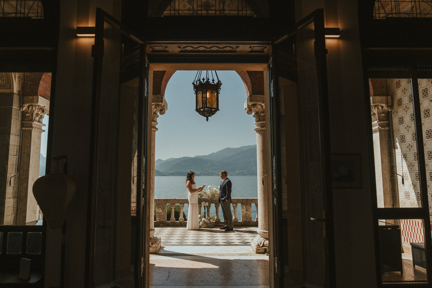 A couple reads elopement vows through the doors of a villa on Lake Como