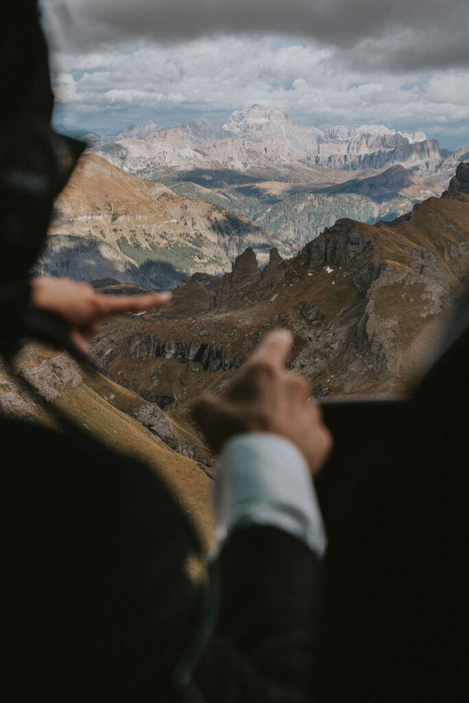 A couple point out the window of a helicopter above the Italian Alps on their Dolomites helicopter elopement day