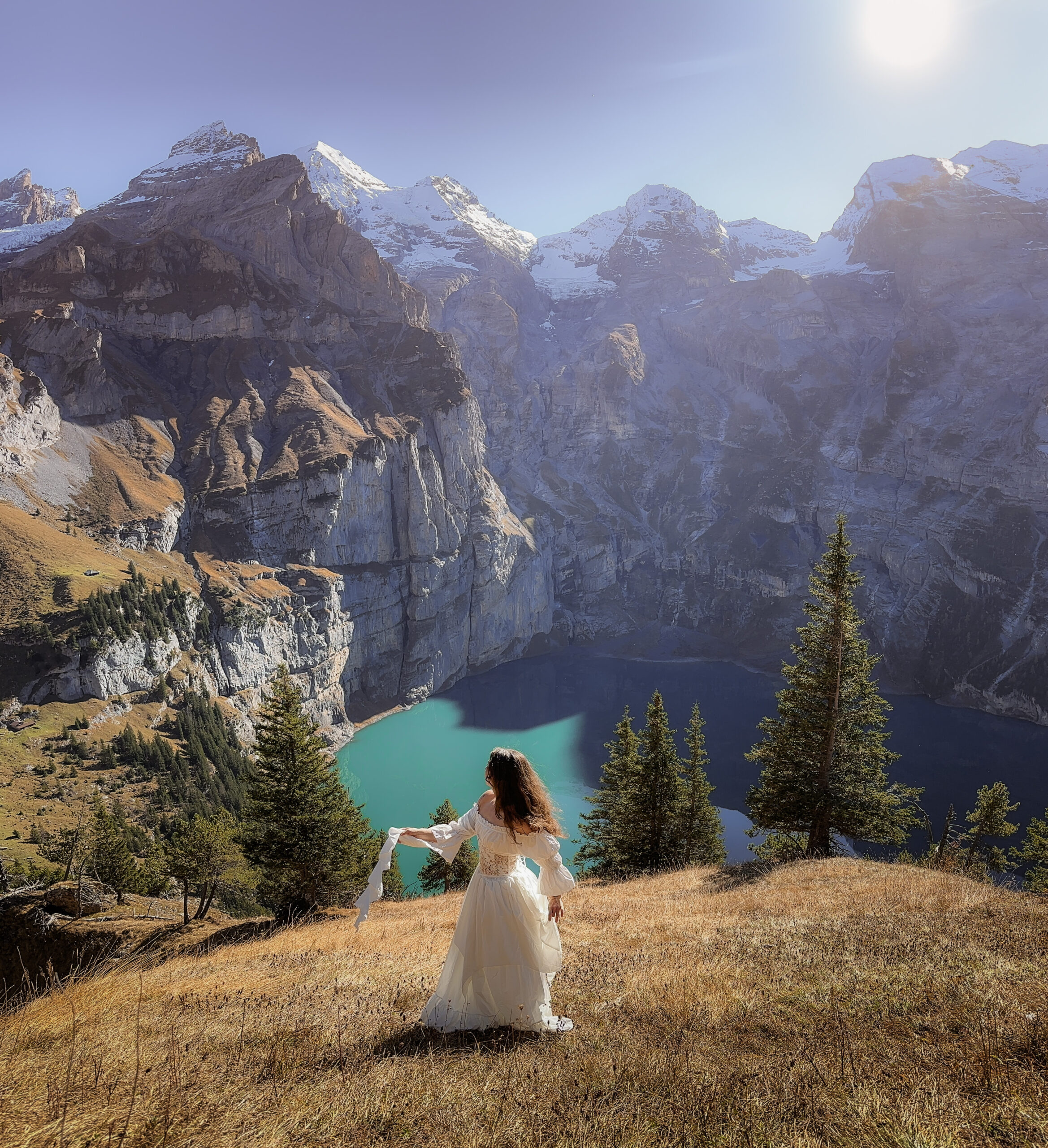 A bride sways in a white dress over Oeschinensee on her elopement day in the European Alps.