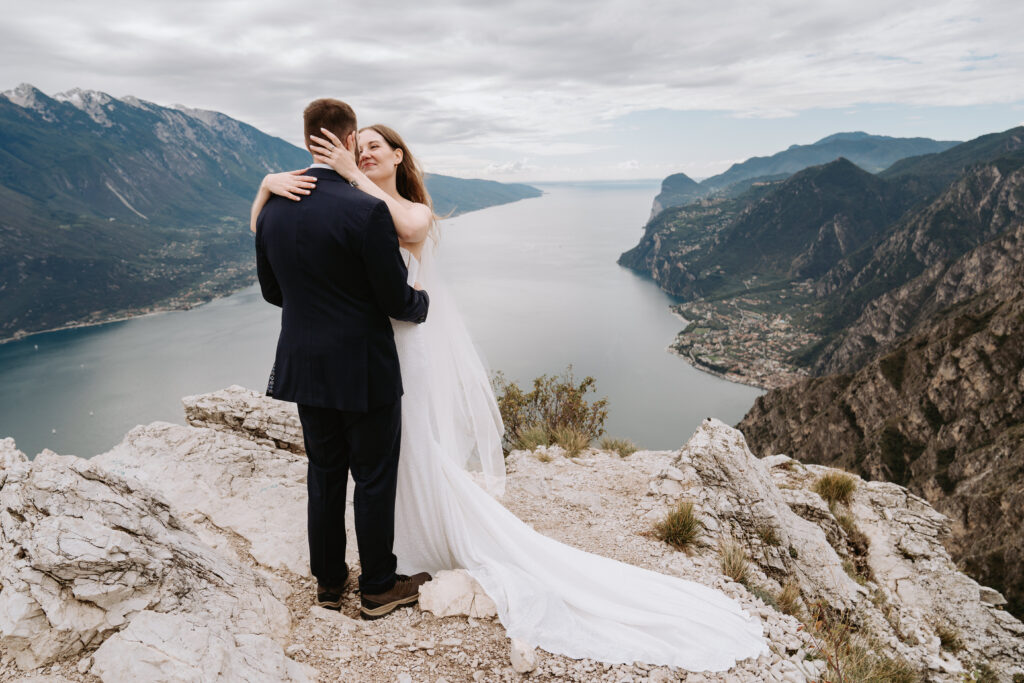 A wedding couple embrace over the Punta Larici viewpoint during their elopement day on Lake Garda