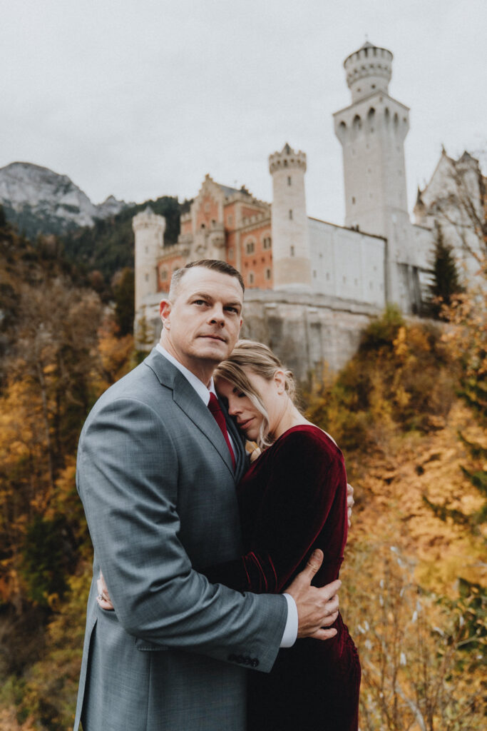 A couple embrace next to castle Neuschwanstein for their wedding photos