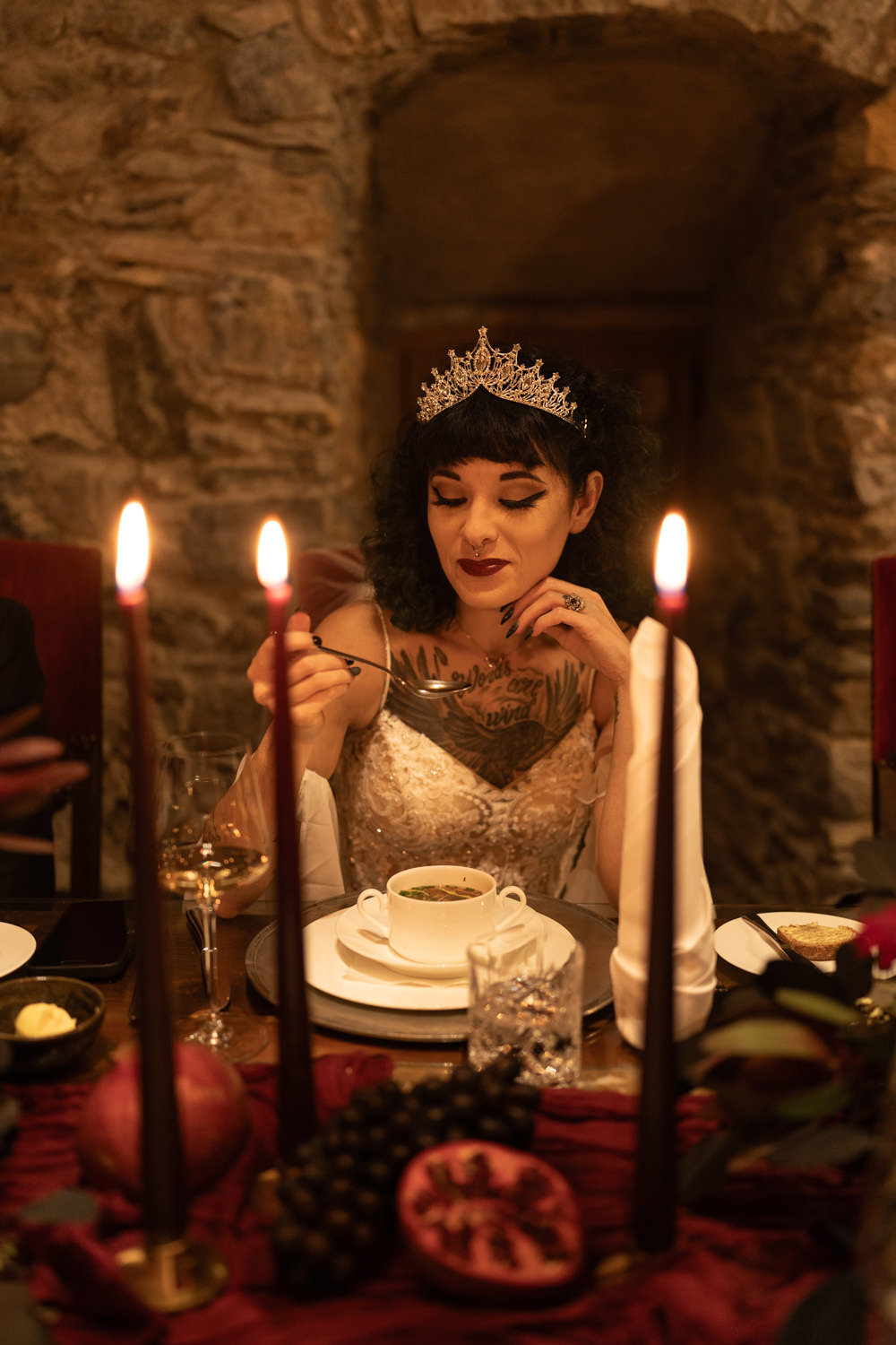 A gothic bride sits at a candlelit dinner reception during her wedding in an Austrian castle