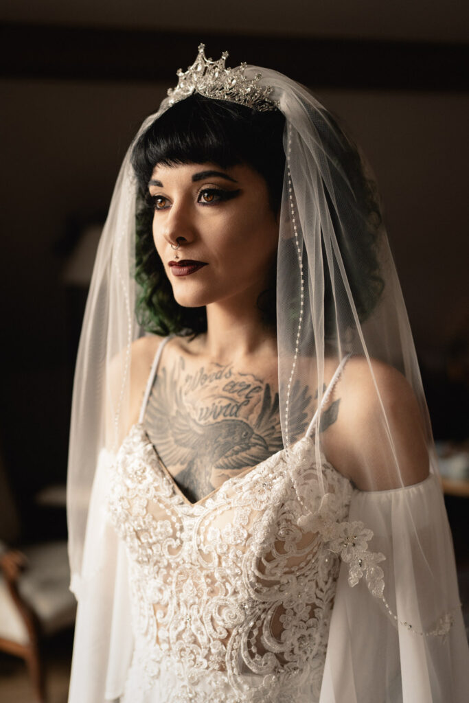 A gothic bride posing in dark makeup, veile and white dress on her wedding day in Austria