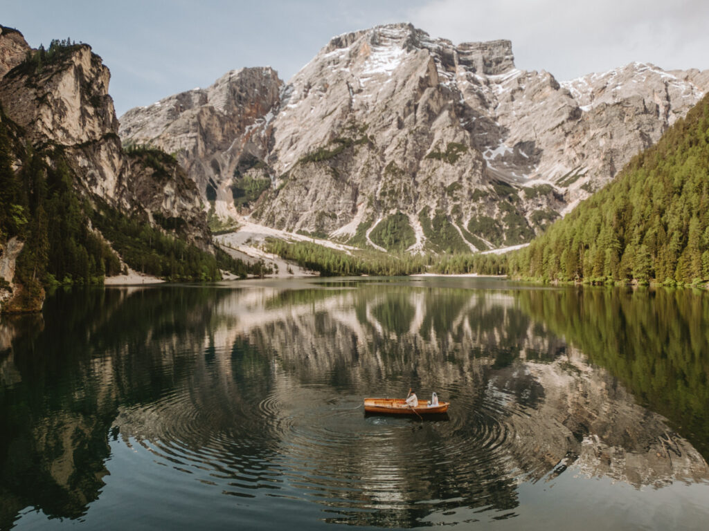 A boat rows on the still waters of Lago di Braies in the Dolomites