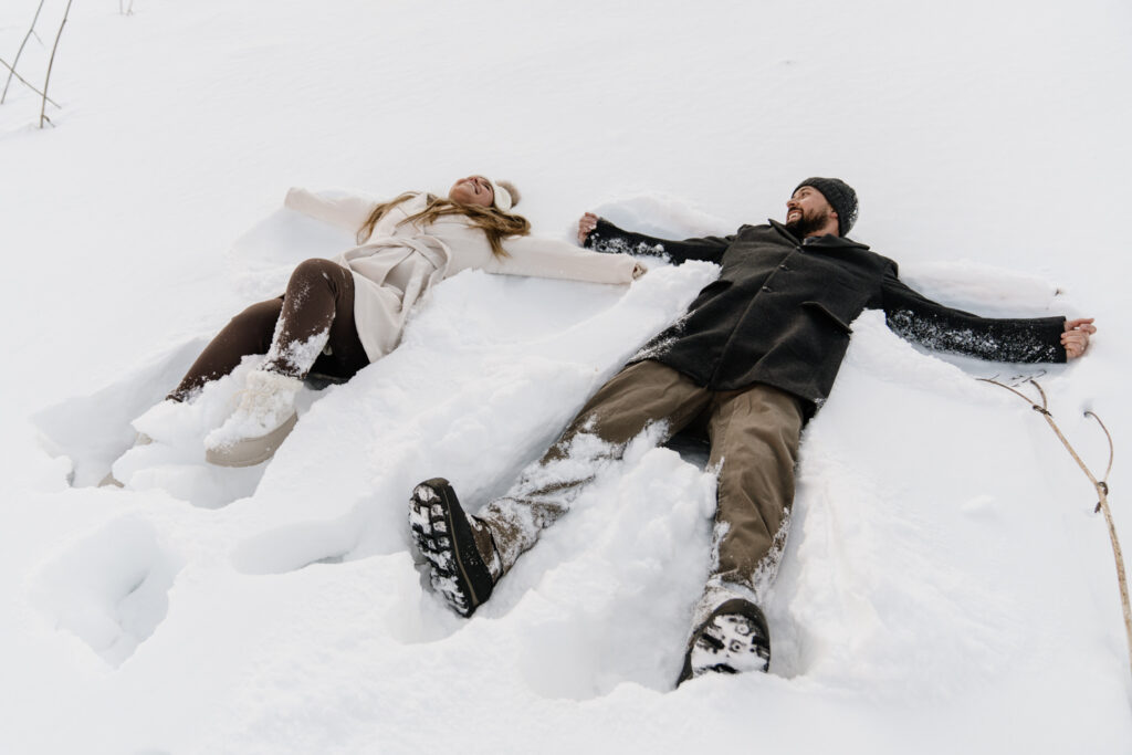 A couple make snow angels during their romantic Dolomites proposal 