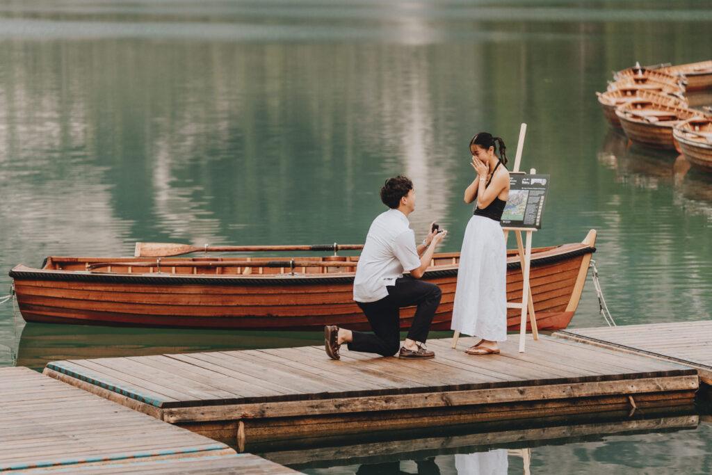 A man proposing to his partner at a boathouse location in the Dolomites with romantic arrangements
